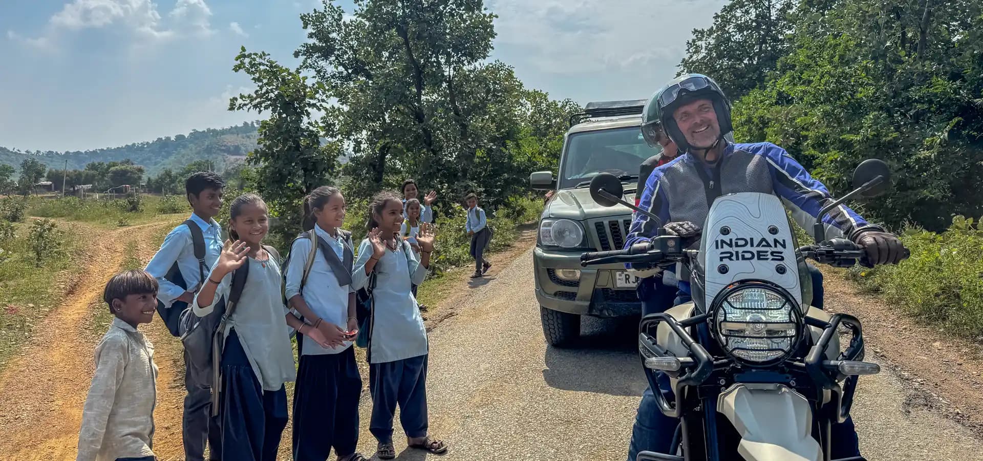 Voyage à moto en Inde avec Indian Rides, rencontre chaleureuse entre un motard et des écoliers indiens sur une route de campagne