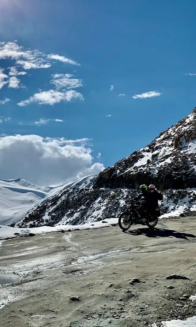 Indian Rides – Aventure moto dans l’Himalaya Motards en Royal Enfield sur une route enneigée du Ladakh
